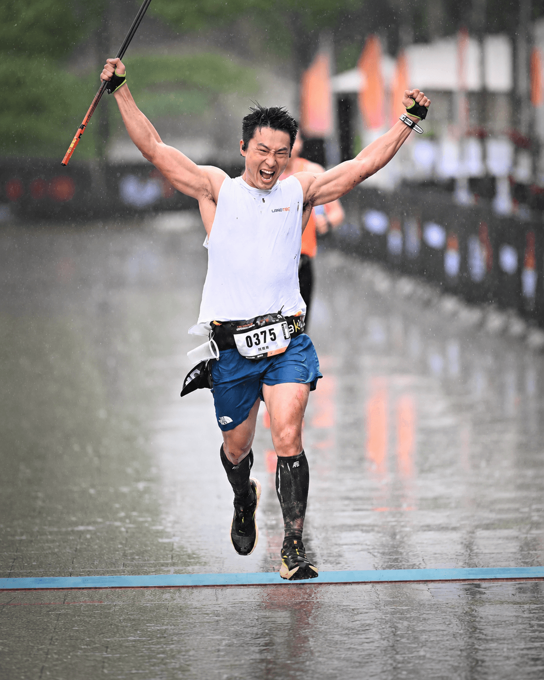 雨中冲过终点线的跑者高举双臂
